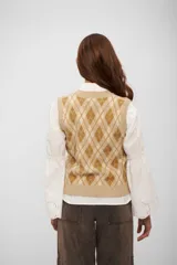 Chaleco tejido de punto con diseño de rombos en tonos beige y marrón, cuello en V y terminaciones acanaladas.