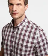 Camisa masculina de manga corta con cuello inglés y abotonado delantero. Estampada con diseño de cuadros en tonos borgoña, gris y blanco.