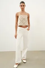Top de escote recto color beige con tirantes finos ajustables con lazadas. Presenta un diseño con apliques de tejido tipo crochet en patrón geométrico de rombos.