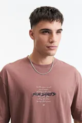 Remera negra de manga corta con corte oversize y cuello redondo. Presenta un estampado pequeño en la espalda con texto en naranja y blanco que dice "Free Spirits Freedom & Waves All Day / Every Day".