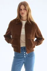 Jeans de tiro alto y corte acampanado, confeccionados en denim con leve elasticidad. Presentan cierre frontal con múltiples botones metálicos visibles, bolsillos de parche delanteros y diseño de perneras anchas desde la rodilla.
