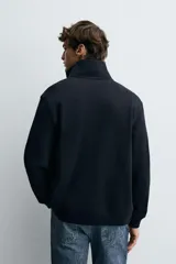 Chaqueta regular fit de tejido técnico interlock de algodón elástico, color azul marino. Presenta cuello subido, manga larga, bolsillos de vivo en la cadera, acabados en rib y cierre frontal con cremallera.