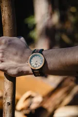 Reloj de pulsera con caja y esfera de madera clara, malla de madera oscura con incrustaciones de madera clara.