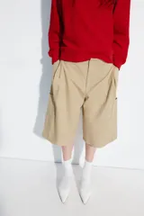 Bermuda larga cargo de color beige, confeccionada en mezcla de algodón. Cuenta con tiro medio, cintura con trabillas, pinzas en el delantero y bolsillos estilo cargo en las piernas.