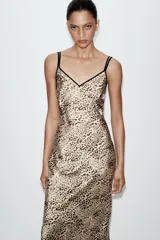 Vestido midi de estilo lencero con estampado animal print, confeccionado en tejido satinado. Presenta escote en pico tanto en el delantero como en la espalda y cuenta con doble tirante fino en color negro.