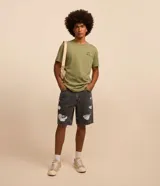 Bermuda masculina de corte slim confeccionada en denim de algodón. Presenta un diseño con efecto destroyed, roturas localizadas y terminación de bajo a hilo. Cuenta con cintura con trabillas, cierre frontal de botón y cremallera, y bolsillos funcionales.