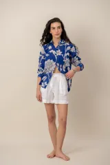 Camisa azul con estampado floral en tono blanco, de manga larga, cuello camisero y cierre frontal de botones.
