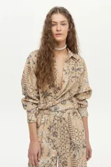 Pantalón de pierna ancha y tiro medio, confeccionado en mezcla de lino y viscosa, con cintura elástica y cordón ajustable. Presenta un estampado artesanal en tonos beige y marrón.