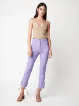 Pantalón de gabardina elastizada color lila, de pierna recta con largo arriba del tobillo y tajos en el ruedo. Tiene cierre delantero, botón, bolsillos laterales y traseros.