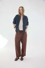 Pantalón de lino marrón de tiro medio, con calce holgado y diseño de piernas amplias. Cuenta con bolsillos traseros, trabillas para cinto y un pin bordado en contraste.