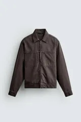 Sobrecamisa de corte regular fit confeccionada en denim de algodón con efecto lavado. Presenta cuello solapa, cierre frontal con cremallera, bolsillos de plastrón en el pecho y mangas largas con puños abotonados.