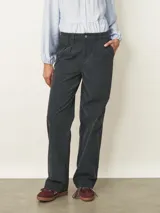 Pantalón de corte recto y tiro medio, confeccionado en tela de pana color azul piedra. Presenta cierre frontal con botón, bolsillos laterales y detalle de pinzas en la cintura.