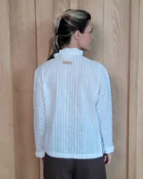 Camisa de manga larga con estampado de rayas verticales en tonos crudo y beige. Presenta cuello alto con volados, cierre frontal con botones dobles y puños con volados.