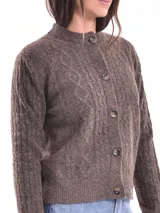 Cárdigan tejido color gris claro con diseño trenzado, cuello redondo y cierre frontal con botones marrones.