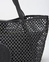 Cartera tote negra de diseño calado con trama tejida, con doble asa de hombro y detalle circular con perforaciones en el frente.