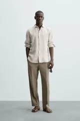 Camisa de corte regular fit confeccionada en tejido de lino, con cuello solapa, manga larga con puños abotonados y cierre frontal de botones.