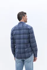 Camisa de manga larga confeccionada en viyela de algodón con diseño a cuadros en tonos verde oscuro. Presenta cuello clásico, cierre frontal con botones y bolsillo aplicado en el pecho.