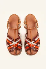 Sandalia plana de cuero blanco con diseño de tiras trenzadas en la parte delantera. Cuenta con una tira ajustable al tobillo con hebilla metálica y suela plana de color negro.