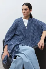 Ruana de punto color azul con estampado de espiga en dos tonos de azul, diseño holgado, con bolsillos y flecos en el borde inferior.