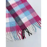Bufanda rectangular de tejido grueso con diseño de cuadros en tonos azul, naranja, gris y beige, terminada con flecos en los extremos.