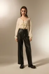 Pantalon de corte recto confeccionado en eco-cuero negro, con tiro medio y costuras horizontales a la altura de la rodilla.