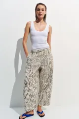 Pantalón estilo pijama de tiro medio, confeccionado 100% en algodón. Cuenta con cintura elástica, bolsillos laterales ocultos en la costura y diseño de corte barrel con estampado de lunares.