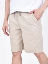 Bermuda de gabardina color beige, con cintura elástica ajustable con cordón, bolsillos laterales y traseros.