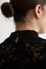 Media polera de encaje color beige, con cuello alto y mangas largas, de diseño translúcido y ajustado al cuerpo.