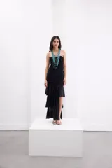 Vestido largo negro strapless de encaje con frunces en el torso, falda asimétrica en capas con volados y breteles removibles.