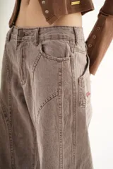 Pantalón de jean color marrón con costuras decorativas verticales en el frente, corte recto y tiro medio.