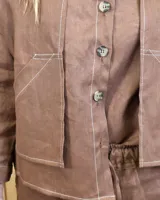 Sobrecamisa de lino color beige, con cuello camisero, cierre frontal de botones carey, mangas largas y bolsillos frontales con solapa.