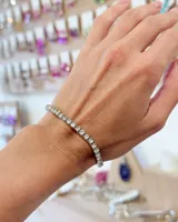 Pulsera tipo tennis de color plateado, compuesta por una hilera de cristales brillantes engarzados. Es un diseño elástico y ajustable.