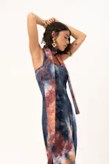 Vestido largo de corte recto y escote strapless, con estampado estilo batik en tonos azul, naranja y bordó. Incluye una bufanda larga integrada al diseño que cae desde el cuello.