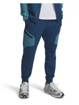 Pantalón tipo jogging Under Armour de corte ajustado, confeccionado en tejido de doble punto elástico y transpirable. Presenta diseño bicolor en tonos azules, cintura elástica con cordón interno, bolsillos laterales abiertos y un bolsillo lateral con cierre. Incluye logo de la marca en la parte superior.