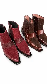 Bota corta de cuero con textura tipo reptil y paneles de gamuza en tono marrón oscuro. Presenta un diseño de punta cuadrada, cierre lateral y un taco cuadrado de madera.