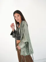 Camisa verde esmeralda con reflejos tornasolados, de corte holgado, con cuello camisero, cierre frontal con botones de nácar y mangas largas con puños abotonados.