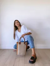 Bolso matero de cuero color beige con textura de reptil y detalles en cuero marrón con textura de cocodrilo. Incluye manijas cortas de cuero marrón y dije de cruz plateada.