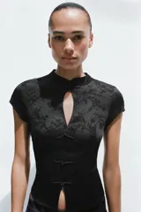 Top negro de manga corta y cuello mao con diseño jacquard de flores, escote en pico y cierre frontal con alamares.