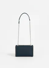 Cartera de hombro color azul marino, con solapa frontal decorada con tachas en forma de estrellas plateadas. Los bordes están adornados con un detalle de cadena entrelazada y la correa es una combinación de cadena plateada y una sección de cuero sintético.