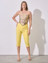 Pantalón capri amarillo de gabardina elastizada con pretina ancha elastizada, bolsillos delanteros simulados y bolsillos traseros aplicados.