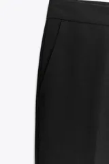 Pantalón negro de tiro alto, corte flare (campana) y pinzas frontales. Presenta bolsillos laterales y falsos bolsillos de vivo en la espalda.