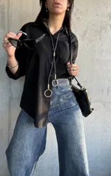 Camisa negra de corte oversize, con cuello clásico, manga larga y bolsillo en el pecho.