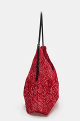 Bolso shopper rojo con estampado tipo bandana y textura plisada. Cuenta con una fina asa de hombro ajustable negra y cierre principal con clip imantado.
