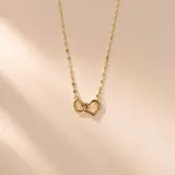 Collar de plata con baño de oro, con cadena de eslabones y dije colgante de dos corazones entrelazados.