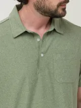 Remera tipo polo de manga corta en color verde sage, con textura jaspeada. Presenta un bolsillo frontal en el pecho, cuello clásico y cierre frontal con botones.