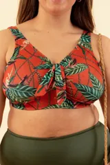 Top de bikini color ladrillo con estampado de hojas verdes y flores. Tiene breteles regulables, nudo en el centro del busto y broche en la espalda.