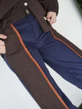 Pantalón de paño combinado con tira de cuero color marrón.