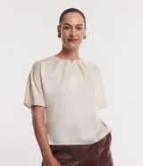 Blusa celeste de tejido satinado con cuello redondo, pliegues en el cuello y manga corta.