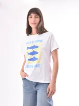 Remera blanca de manga corta con estampado frontal que incluye el texto 'Isola di Capri' y 'Amalfi Coast', junto a un diseño de tres peces azules sobre un fondo de damero amarillo.