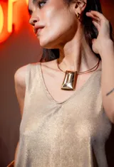 Collar dorado tipo cuellera con dije rectangular grande.